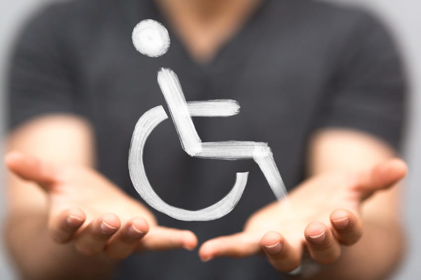 photo avec arrière plan flouté montrant 2 mains ouvertes paumes vers le haut sous un pictogramme de fauteuil roulant pour personne handicapée