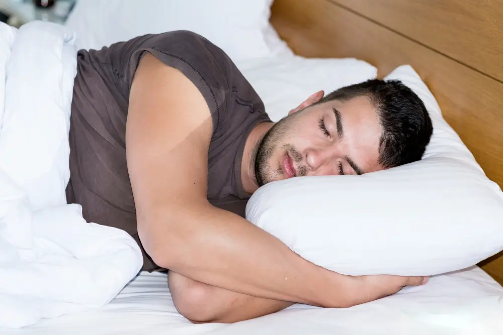 photo d'un jeune homme endormi allongé sur un lit et portant un t-shirt