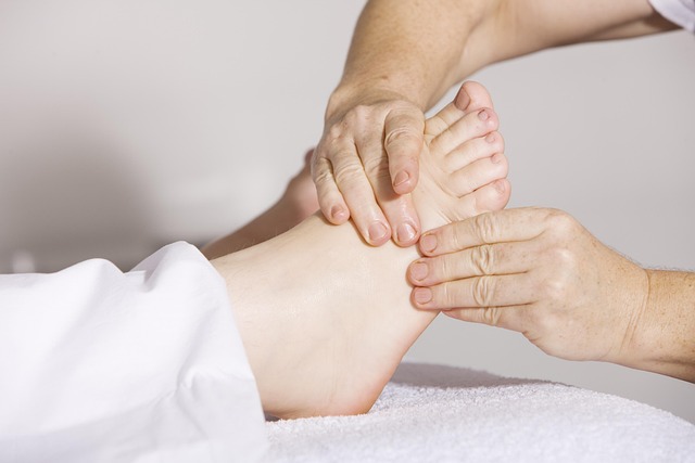 Photo montrant un pied et les mains d'un praticien exerçant un massage lors d'un séance de réflexologie plantaire