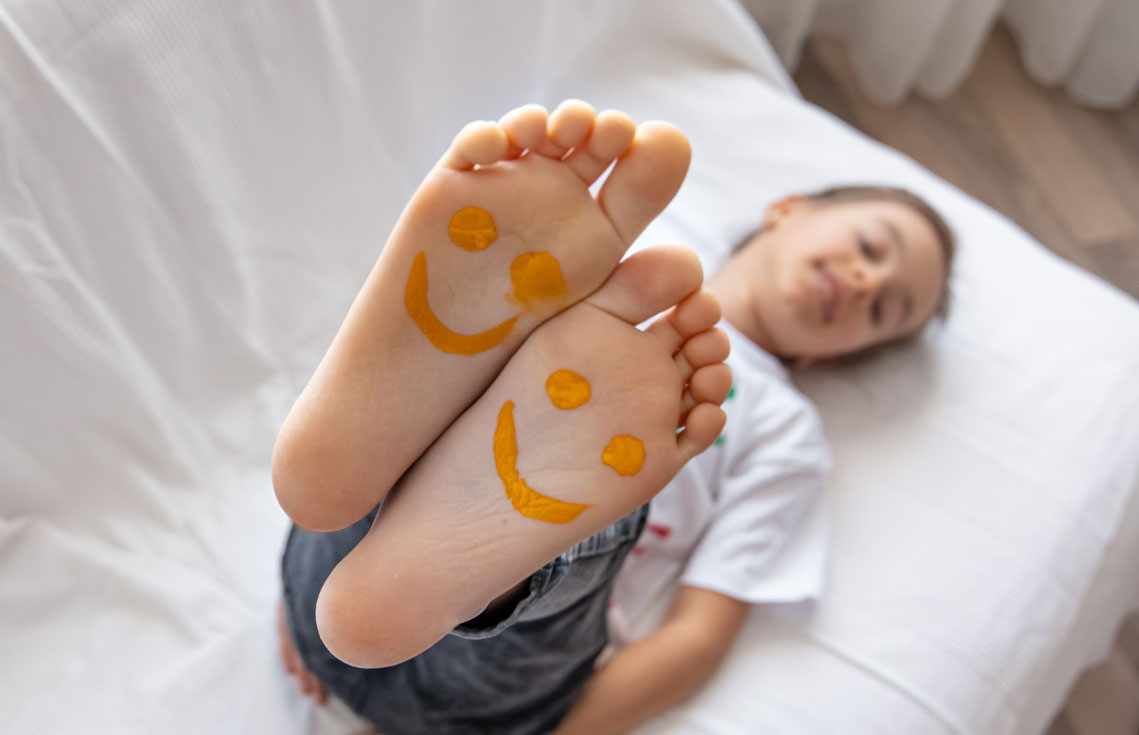 photo d'un enfant allongé pieds en hauteur avec motifs de sourire